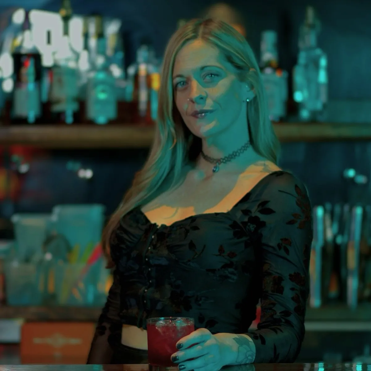 Bartender with drink in teal light